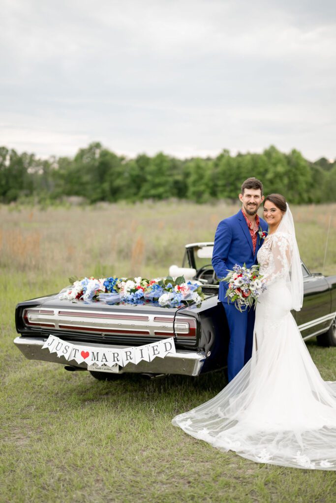 a man and woman in a wedding dress posing in front of a car
